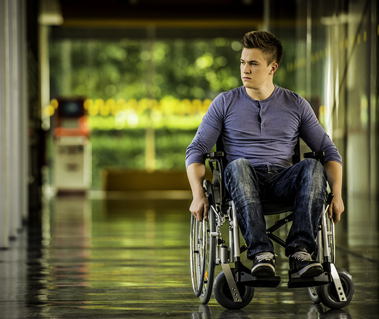 Young Man in a Wheelchair Young man in wheelchair traveling down hallway