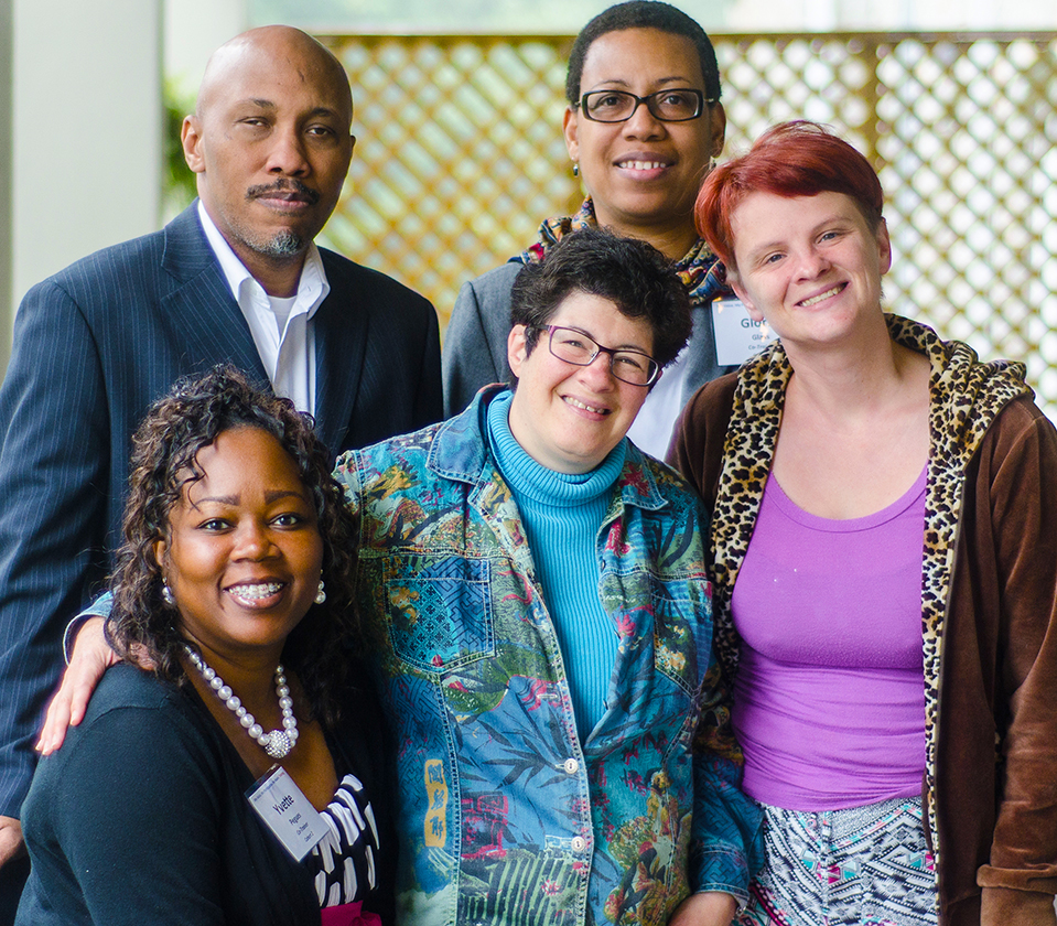 Diverse group of men and women with and without disabilities posing and smiling at the camera
