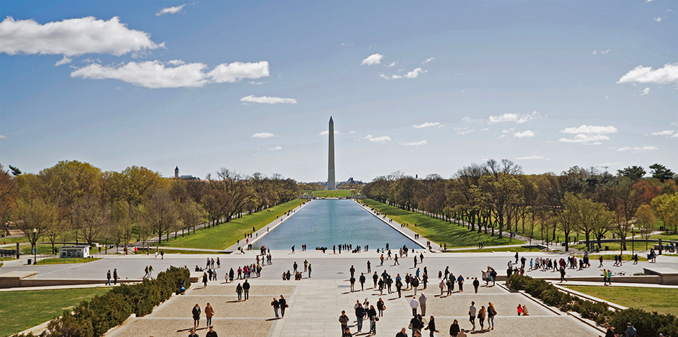 View of the Washington monument and Lincoln Memorial Reflecting Pool in early fall, with groups of tourists milling around