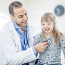 Doctor with stethoscope screening smiling young girl with disability